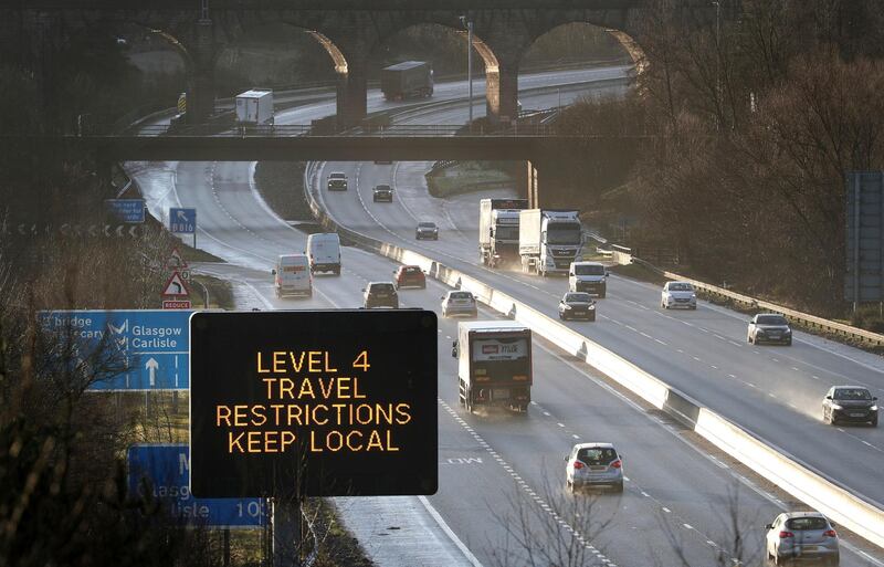 A traffic information board advises drivers to keep their travel to local trips as traffic moves along the M80 motorway near Banknock, Scotland. AP Photo