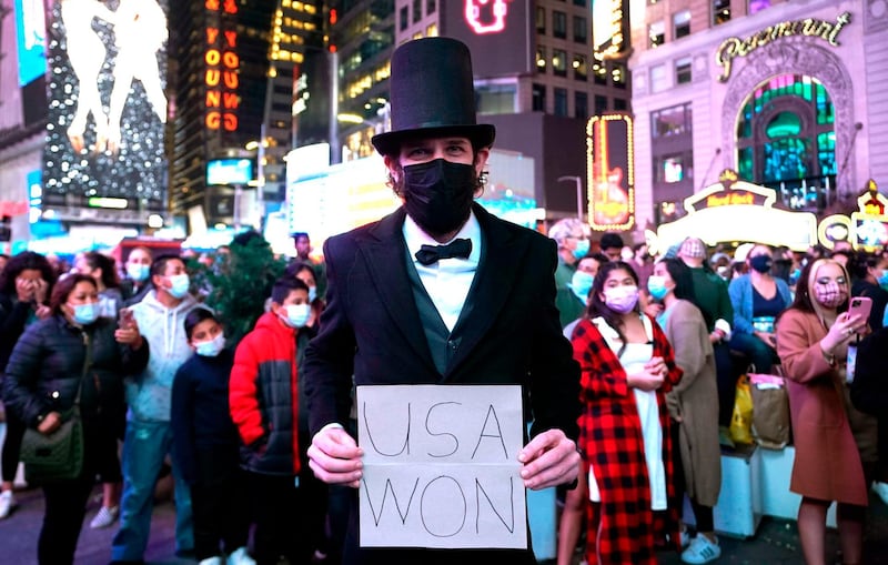 A man dressed as Abraham Lincoln holds a sign as people celebrate in the streets before US president-elect Joe Biden delivers remarks from Delaware  AFP