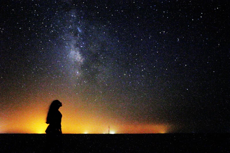 A woman looks at the Milky Way rising in the night sky in Kuwait's Al Salmi desert.