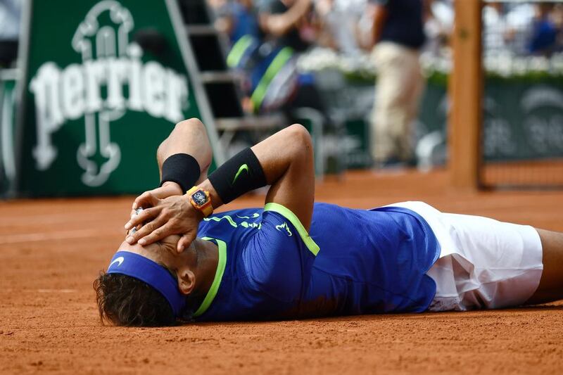 Rafael Nadal falls to the court as he celebrates after winning the men’s title. AFP