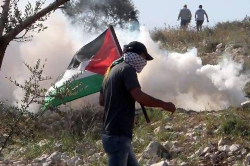 A Palestinian protester runs away from a tear gas canister fired by Israeli security forces during clashes in the village of Kfar Qaddum, near Nablus in the West Bank on Friday. Jaafar Ashtiyeh / AFP