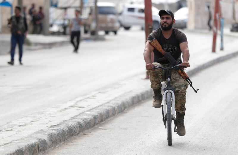 A Turkey-backed Syrian rebel fighter rides a bicycle down a street in the border town of Tal Abyad, Syria. Reuters