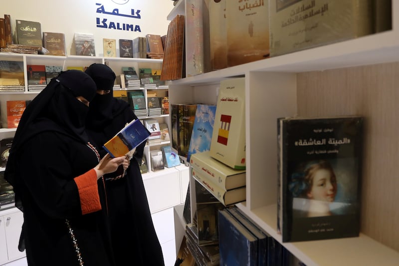Two women read a book during the Riyadh International Book Fair.
