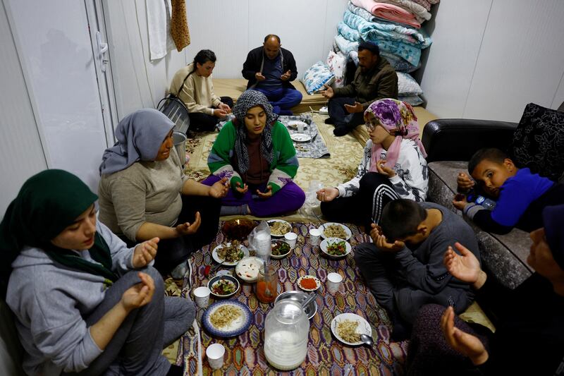 Members of the Arslan family pray at dinner in one of the three container homes where they live. Reuters