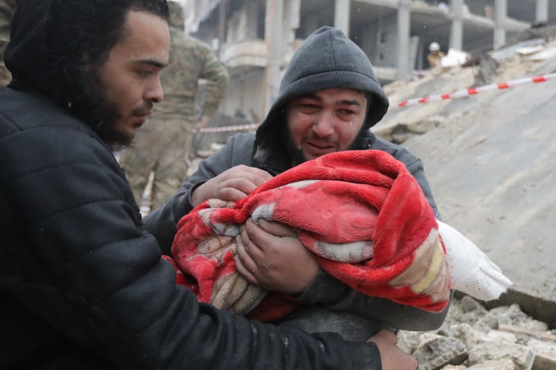 A Syrian man weeps as he carries the body of his son who was killed in an earthquake in the town of Jandaris. AFP