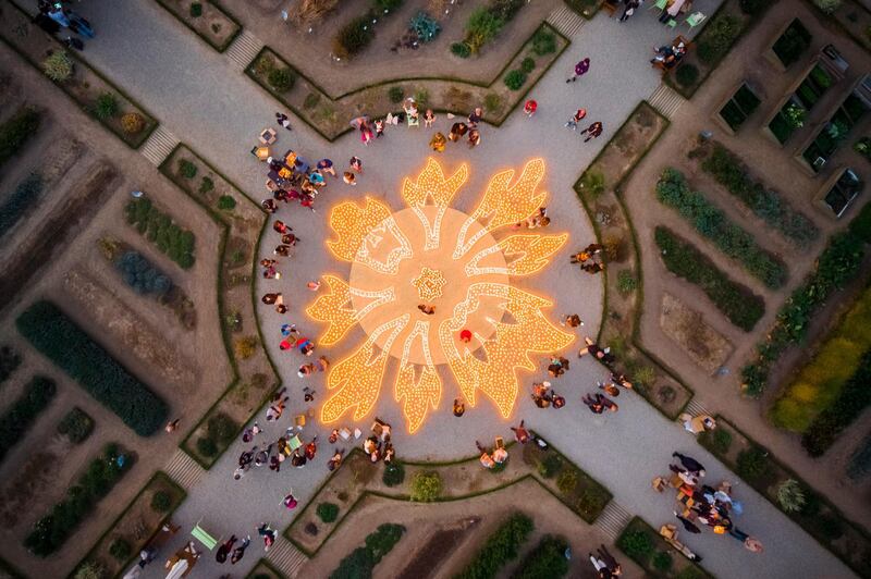 People stand around candles viewing an artistic installation entitled 'Flowers of Fire' (Fleurs de Feu) by Spanish artist Muma in the vegetable garden of the castle of Prangins, Switzerland. EPA