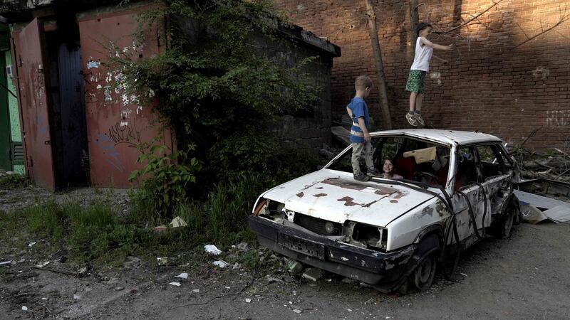 Children play on a destroyed car in a residential area of Mariupol. AFP