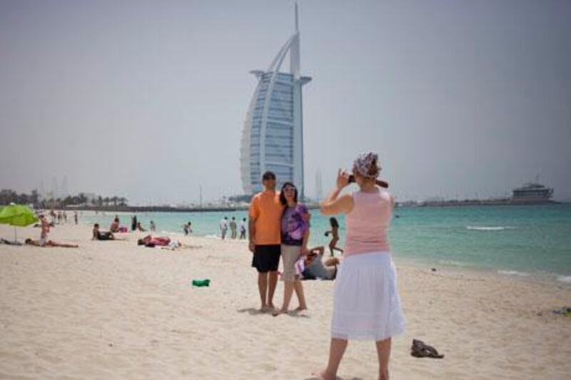 Dubai, United Arab Emirates - May 23 2013 - Tourists from Turkey take pictures at the public beach by Burj Al Arab after being dropped off there by a tour bus. STOCK. (Razan Alzayani / The National)  