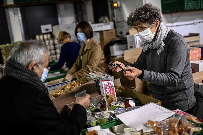 A volunteer (R) of the charity 'Les Restos du Coeur' distributes food to a man in need at a centre of the charity in Paris on October 13. Christophe Archambault/ AFP