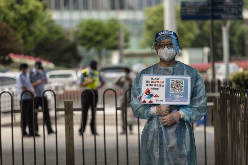 A transit worker wearing protective gear holds up a location tracking code outside a subway station in Shanghai. China's financial capital reported its fewest Covid-19 cases in almost three months as residents celebrated a significant easing of curbs on movement. Bloomberg
