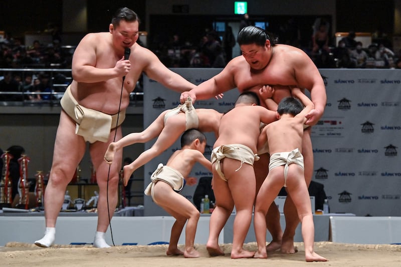 Retired Mongolian-born wrestler Hakuho, left, watches on as young participants try to push Japanese wrestler Hakuoho out of the ring during a bout in Tokyo. AFP