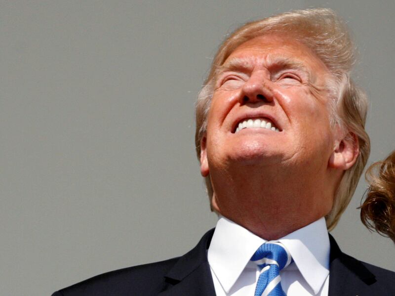 US president Donald Trump looks up towards the solar eclipse without his protective glasses on as he views the eclipse from the Truman balcony of the White House in Washington, US. Kevin Lamarque / Reuters