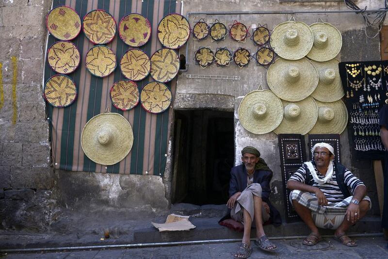 Yemeni men sit beneath handicrafts displayed for sale in the Old City of Sanaa. Yahaya Arhab / EPA