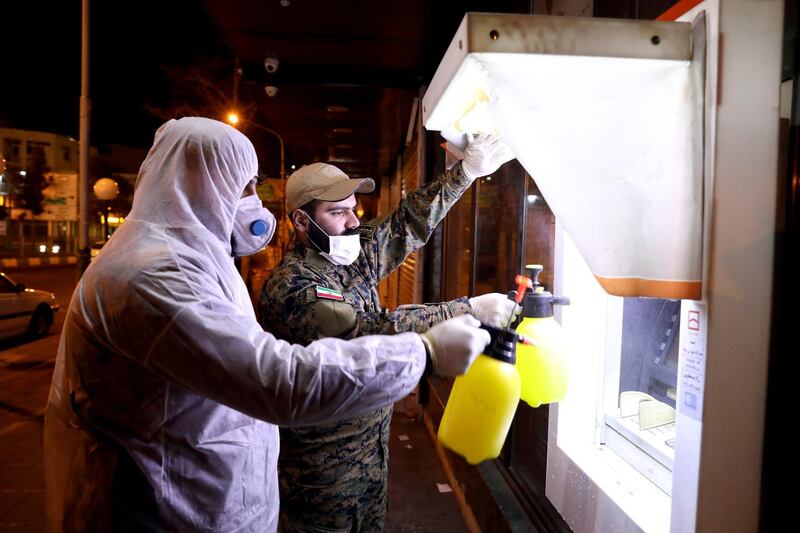 Revolutionary Guard members disinfect an ATM machine to help prevent the spread of the new coronavirus in Tehran, Iran. AP Photo