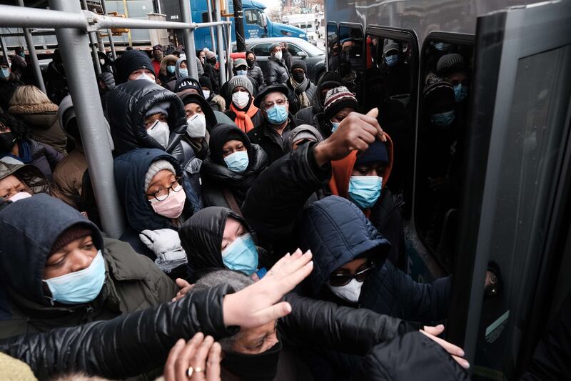 People rush to receive Covid-19 testing kits from city workers  in the Brooklyn area of New York. The city is handing out thousands of the kits, which include two tests per box, as part of efforts to reduce the surge of people in long lines at testing sites. AFP