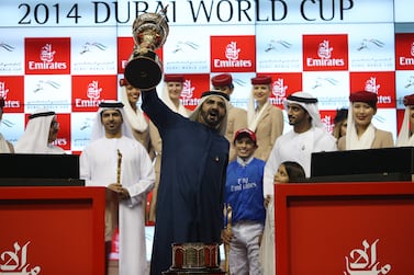 Sheikh Mohammed bin Rashid, Vice President of UAE and Ruler of Dubai, lifts the Dubai World Cup as he is flanked by De Sousa, the jockey, right, and Saeed bin Suroor, the trainer. Pawan Singh / The National
