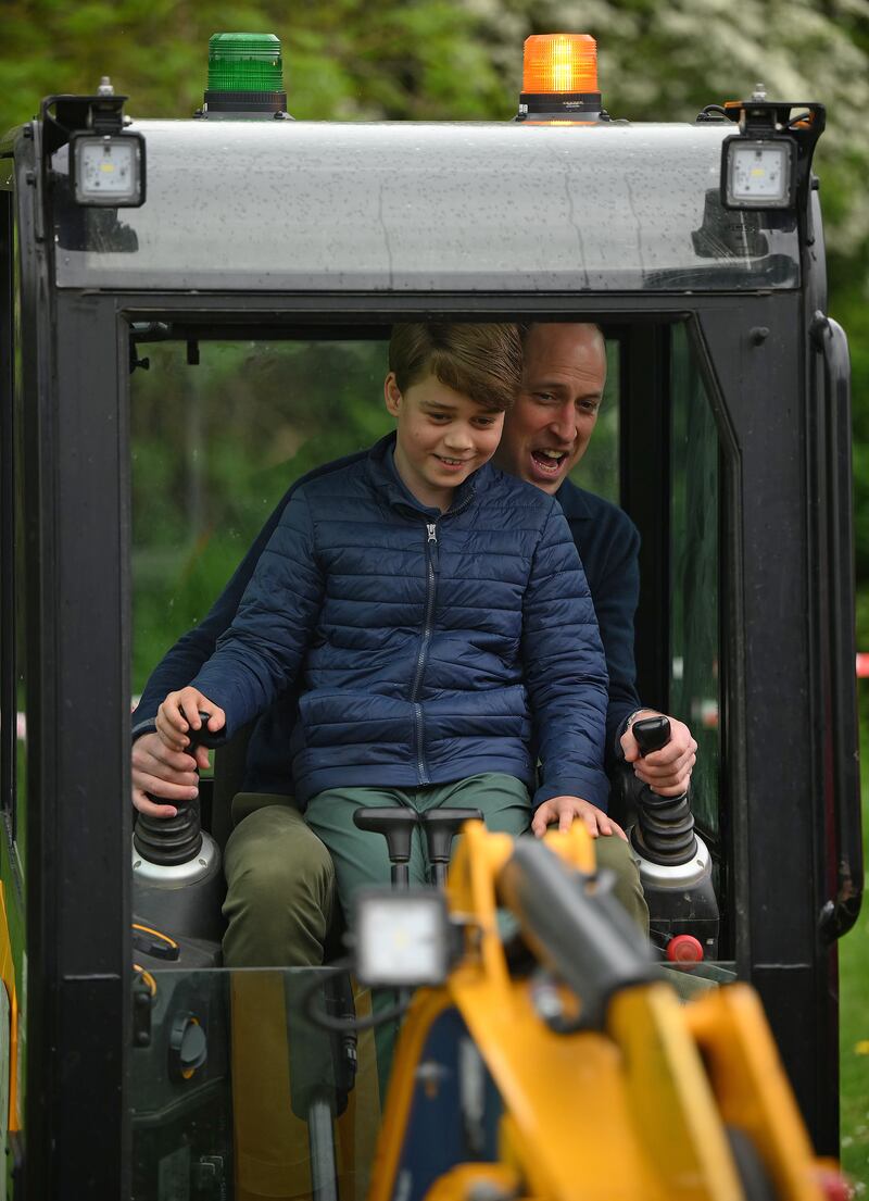 Prince William and his son Prince Louis try out using the controls of a digger in the scout hut grounds. Getty