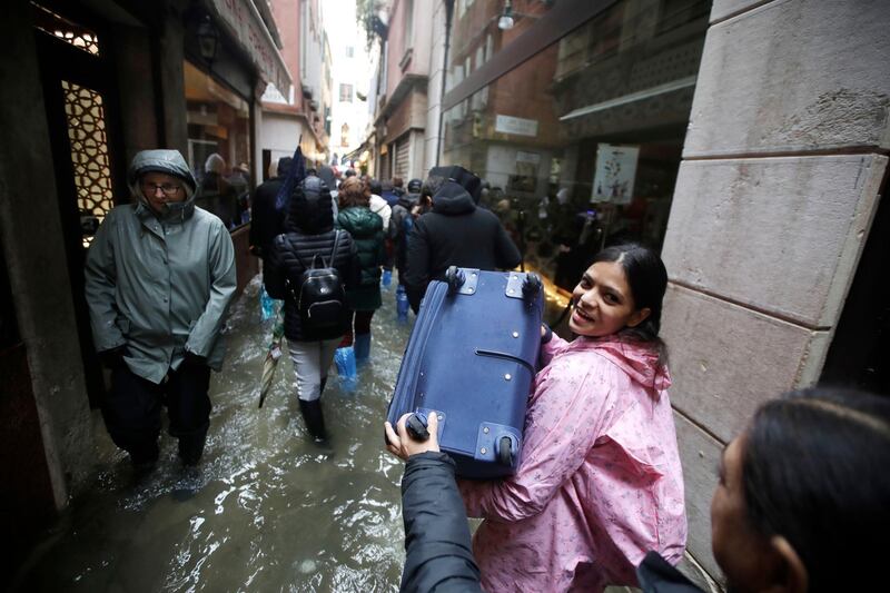 Tourists carry their luggage as they wade through water in a flooded Venice. AP