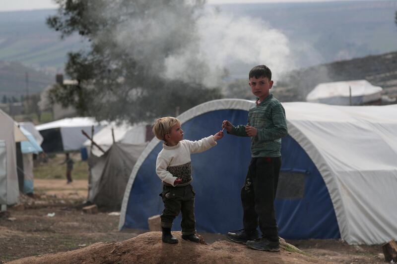 Internally displaced Syrian boys stand near tents in Azaz, Syria. REUTERS