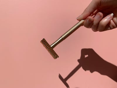 Woman holding razor in front of pink background