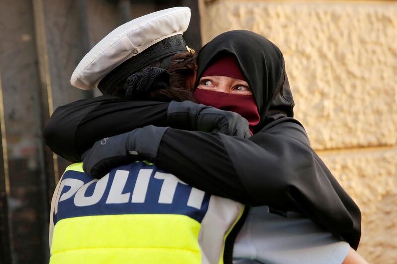 QUALITY REPEAT - Ayah, 37, (R) and wearer of the niqab weeps as she is embraced by a police officer during a demonstration against the Danish face veil ban in Copenhagen, Denmark, August 1, 2018.  REUTERS/Andrew Kelly
