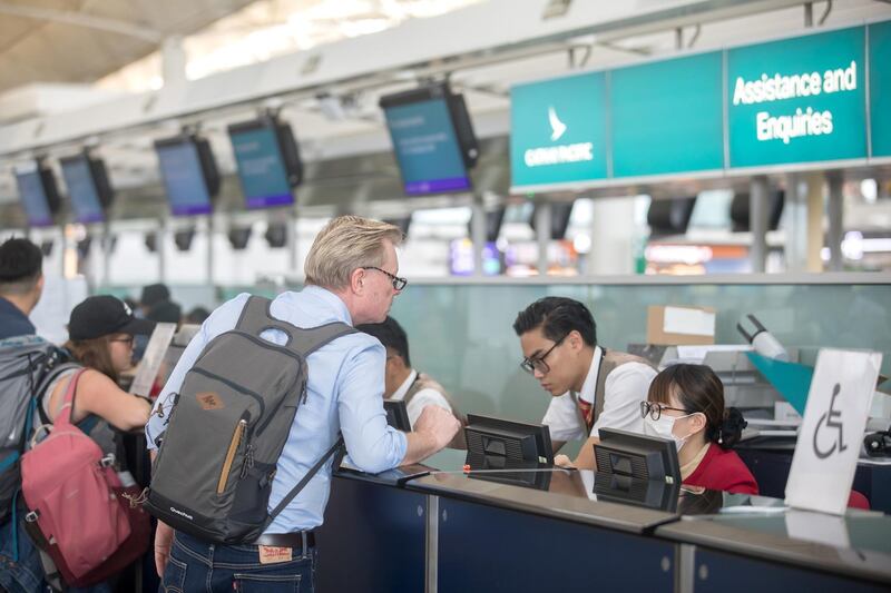 Travellers speak to Cathay Pacific Airways employees at the company's check-in counter at the Hong Kong International Airport. Bloomberg