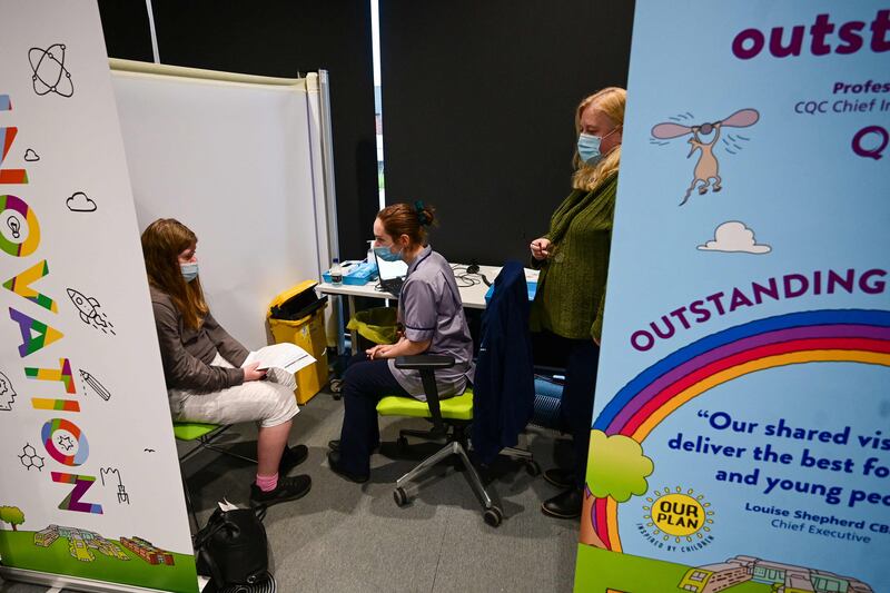 Health workers speak with a patient inside a vaccination centre in Liverpool. AFP