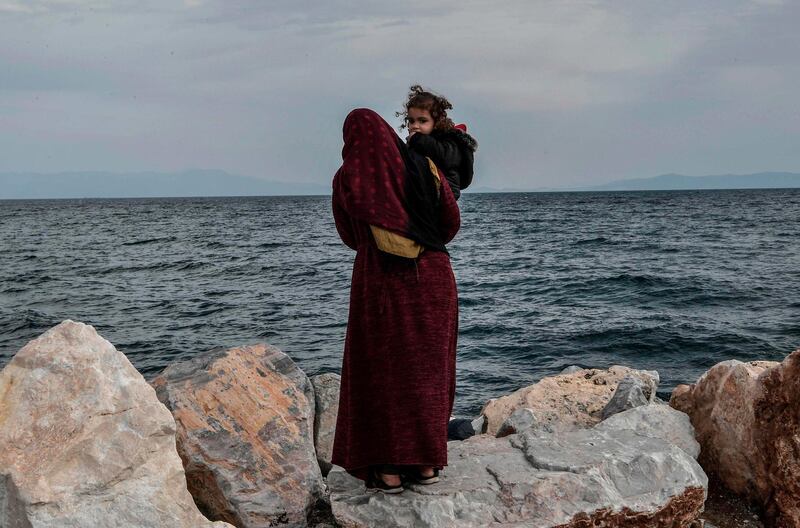 A refugee mother holds her child  as she stands looking out at sea at he port of Mytilene on the Greek Island of Lesbos on March 7, 2020, close to where a Greek military carrier is being used to accomodate refugees and migrants who arrived on the island after March 1, 2020.   / AFP / LOUISA GOULIAMAKI
