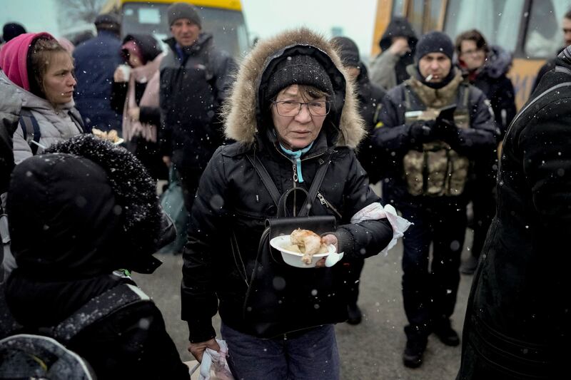 A woman rescued from the outskirts of Kyiv holds a plate of food after arriving at a triage point in the Ukrainian capital. AP