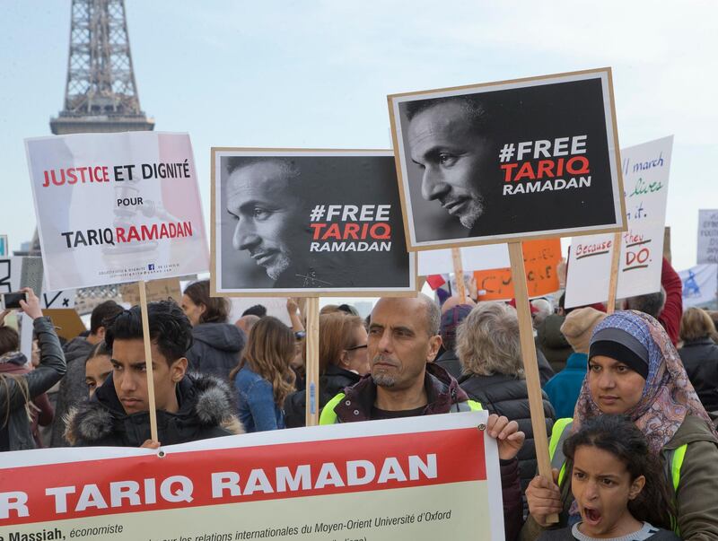 Supporters of Muslim scholar Tariq Ramadan stage a protest near the Eiffel Tower in Paris, France, Saturday, March 24, 2018. Prominent Muslim scholar Tariq Ramadan is being held in jail after he was handed preliminary rape charges based on allegations from two women. Placard left reads, "Justice and Dignity for Tariq Ramadan". (AP Photo/ Michel Euler)