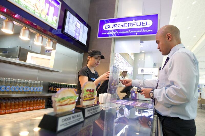 Mirchelle Pamintuan takes customer Glenn Gawler's lunchtime order at BurgerFuel in Mirdif City Centre, Dubai. Sarah Dea / The National