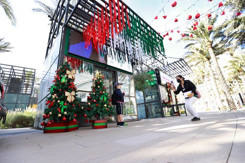 A young Expo visitor gets his photo taken alongside colourfully decorated Christmas trees.