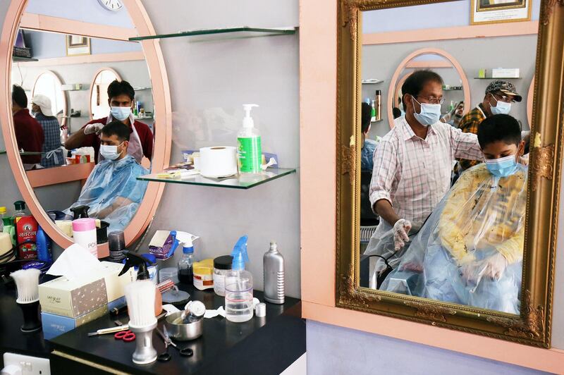Mask-clad Kuwaitis get haircuts at a barber's shop in the capital Kuwait City on February 4, 2021, during the coronavirus pandemic crisis. (Photo by YASSER AL-ZAYYAT / AFP)