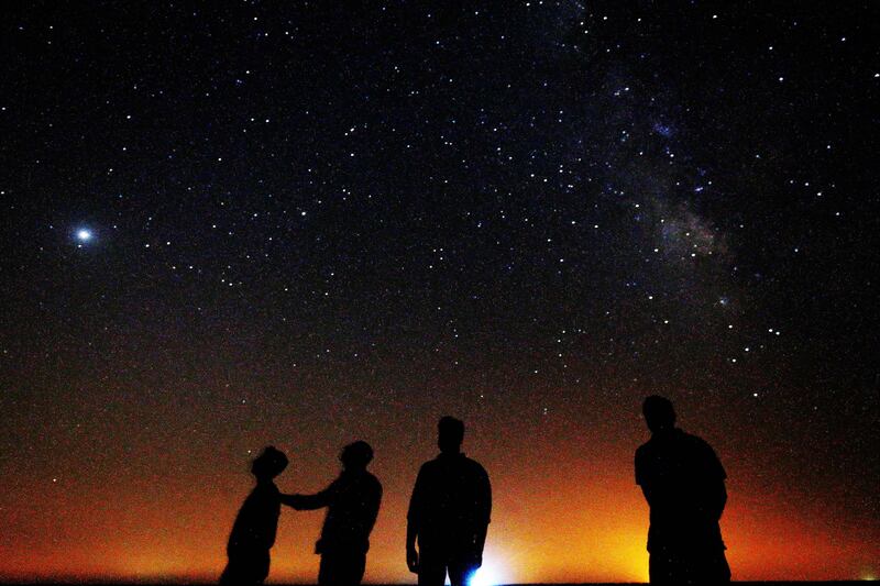 People look at the Milky Way galaxy rising in the night sky in Kuwait's Al Salmi desert, 120Km north of the capital.