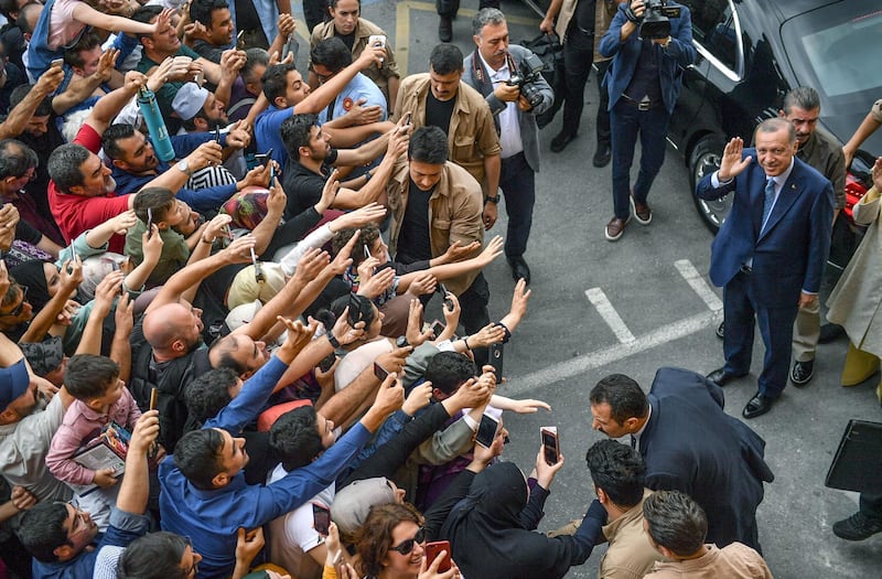 TOPSHOT - Turkey's President Recep Tayyip Erdogan, leader of the Justice and Development Party (AKP) is greeted by supporters as he and his wife leave the polling station after casting their votes during snap twin Turkish presidential and parliamentary elections in Istanbul on June 24, 2018. Erdogan has won tightly-contested presidential polls, the election authority said on June 25, extending his 15-year grip on power as the opposition complained bitterly about the conduct of the vote count. / AFP / BULENT KILIC
