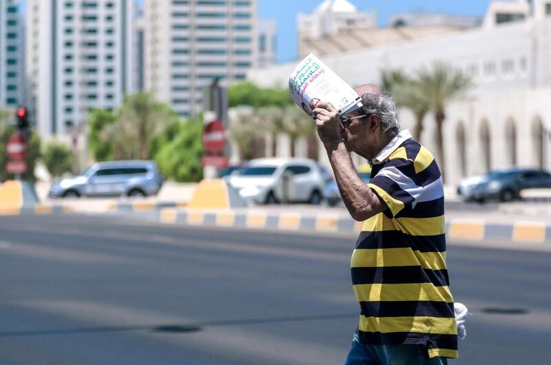 Abu Dhabi, United Arab Emirates, July 15, 2019.  Standalone weather images.  A man covers his head with a newspaper while crossing a street at downtown Abu Dhabi.
Victor Besa/The National
Section:  NA
Reporter: