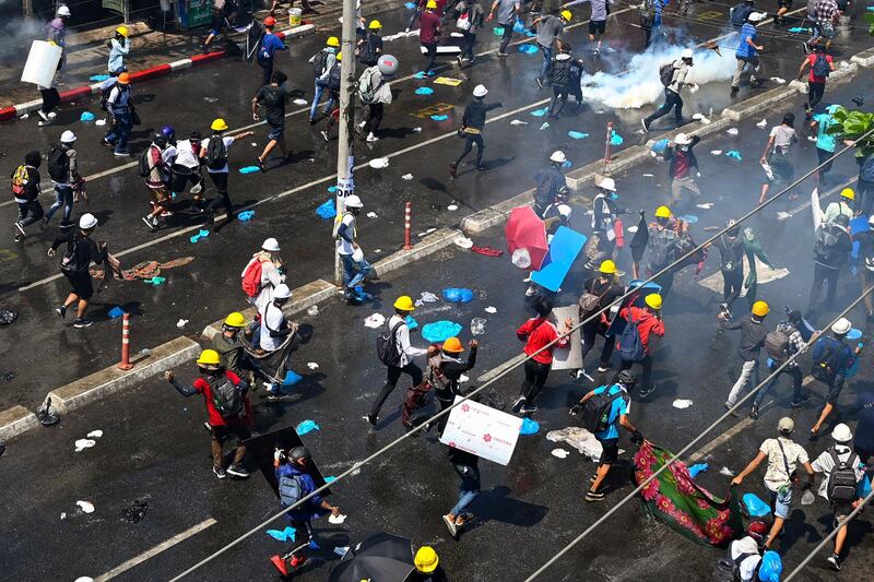 Anti-coup protesters in Myanmar run after tear gas was fired during a demonstration in Yangon. AFP