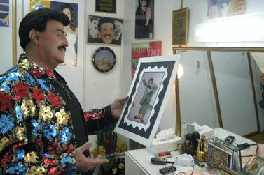 Egyptian comedy star Samir Ghanem looks at an old picture of himself in the role of the famous clown character Fattuta. AFP