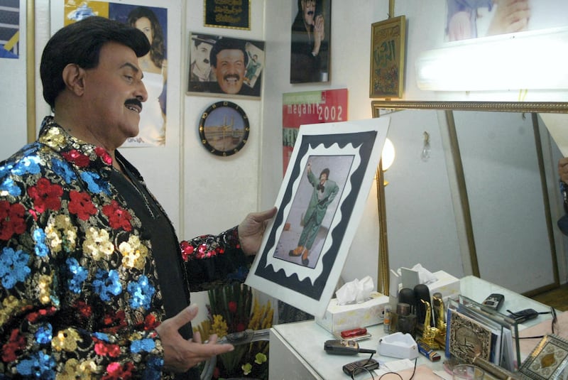 Egyptian comedy star Samir Ghanem looks at an old picture of himself in the role of the famous clown character Fattuta 15 August 2005 in the make up room at Cairo's Al-Rihani Theatre, where he has been starring for the past five years in the hit musical comdey 'Do, Re, Mi, Fasolia'. AFP PHOTO/AMRO MARAGHI (Photo by AMRO MARAGHI / AFP)