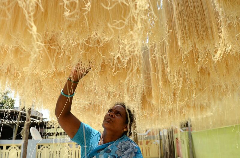 An Indian worker arranges strands of vermicelli noodles to dry at a factory during on the outskirts of Chennai on June 1, 2018. - Sheer khurma, or sheer khorma, is a sweet dish prepared with vermicelli noodles and eaten during the during the Islamic holy month of Ramadan. (Photo by ARUN SANKAR / AFP)