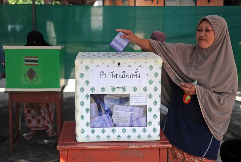 A woman casts her vote in a ballot box at a polling station in Narathiwat province. Voting began in Thailand's troubled election but anti-government protesters forced the closure of more than 10 per cent of polling stations nationwide, an election commission official said. AFP 