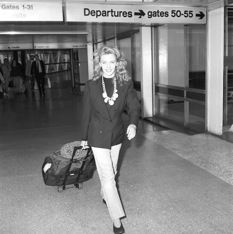Kylie Minogue, in a black blazer, walks through Heathrow Airport ahead of the Royal Variety Show in London, England, on November 21, 1988. All photos: Getty Images