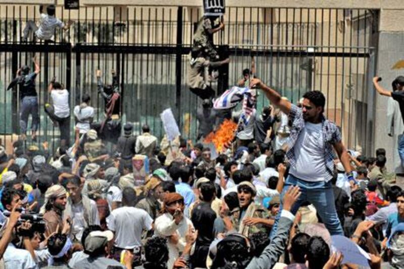 A Yemeni protester burns a US flag as others storm the US embassy in Sanaa.