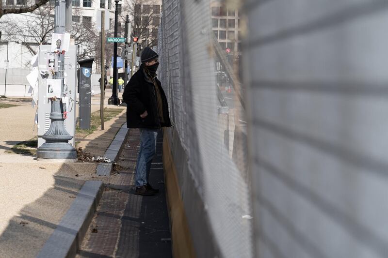 A man looks through the mesh security fence at the US Capitol building. Willy Lowry / The National