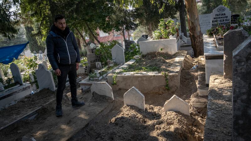 Baris Yapar stands by his grandparents' graves. He believes they could have been saved had rescue and recovery teams arrived faster 