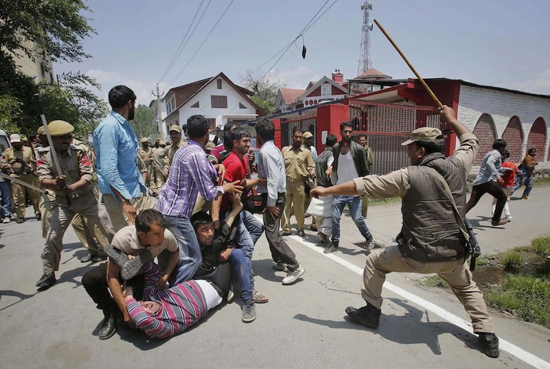 An Indian policeman approaches to beat Kashmiri government employees during a protest in Srinagar, India.  Mukhtar Khan / AP Photo