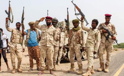 A picture taken on June 22, 2018 shows Sudanese soldiers fighting alongside Yemen's Saudi-backed pro-government forces against the Huthi rebels as they salute with their hands and firearms before a tracked vehicle on the side of a road near Al-Jah, about 50 kilometres southwest of the Red Sea port city of Hodeida.  / AFP / Saleh Al-OBEIDI
