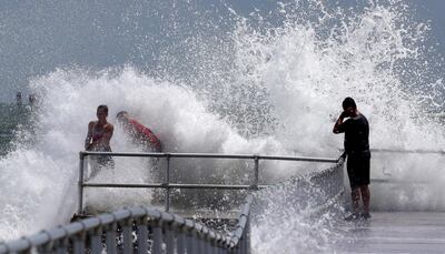 Residents hang on to the railing as a wave generated by Hurricane Dorian crashes into the jetty at Lighthouse Point Park in Ponce Inlet, Fla., Monday, Sept. 2, 2019. (Joe Burbank/Orlando Sentinel via AP)