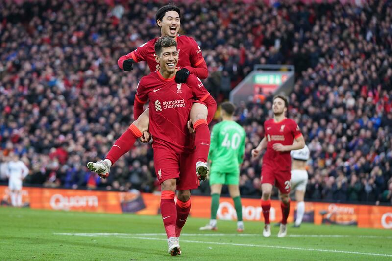 Takumi Minamino celebrates with Roberto Firmino after scoring Liverpool's third goal during the Premier League match against Brentford at Anfield on Sunday, January 16, 2022. AP