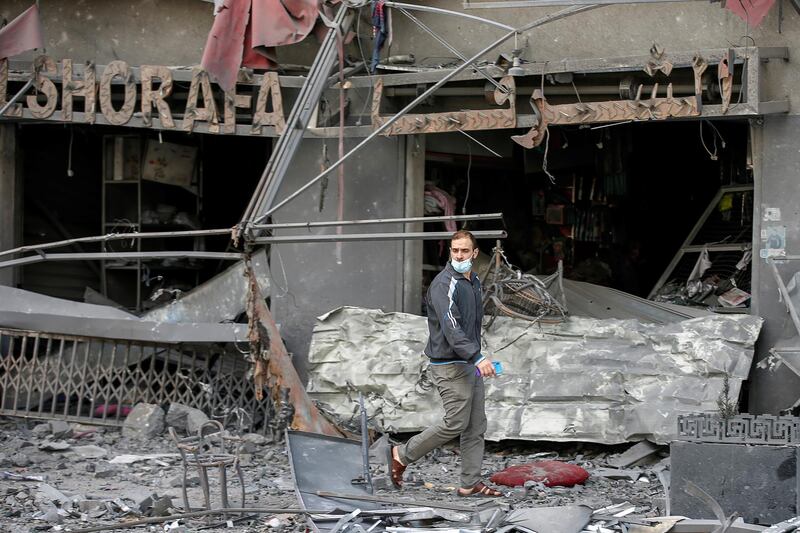 A Palestinian man stands outside a damaged shops in the aftermath of Israeli air strikes that destroyed a tower building. Reuters
